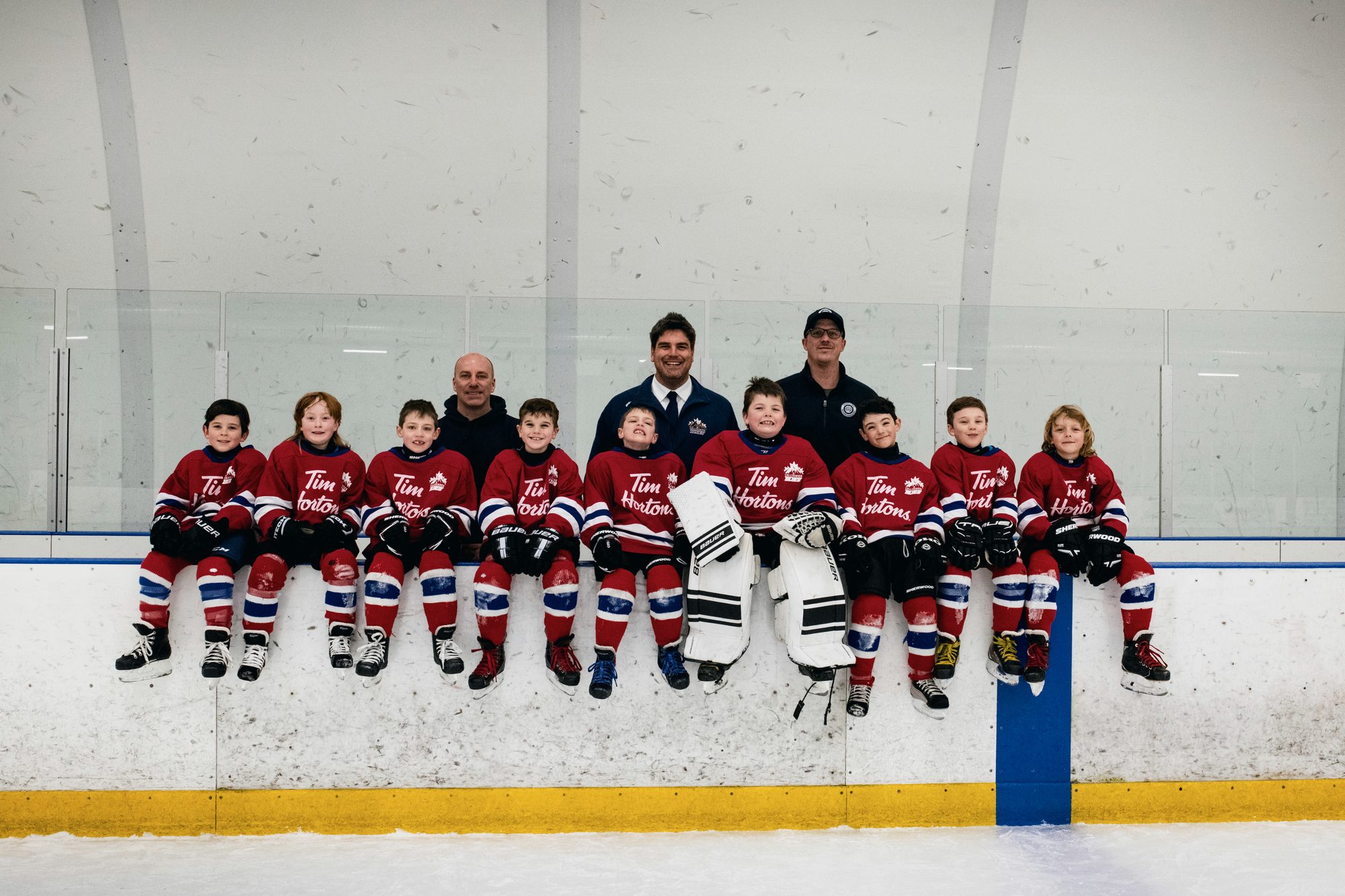Jon with the novice hockey team he coaches, the players sitting along the boards.